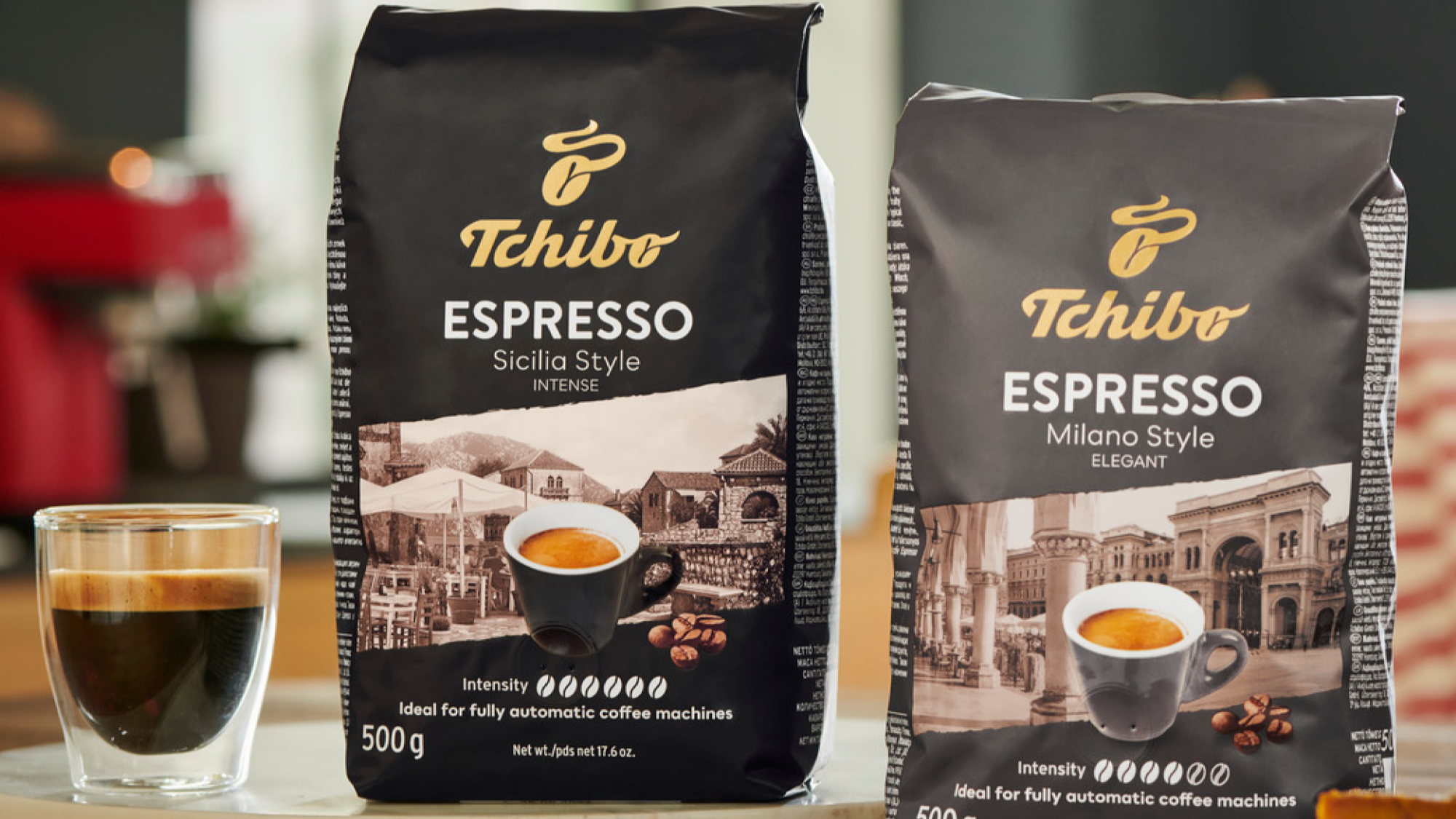 Two Tchibo Espresso coffee bags on a table with a glass of coffee.
